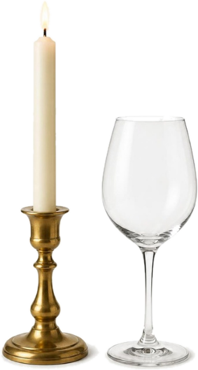 Taper candle in a brass holder beside a wine glass